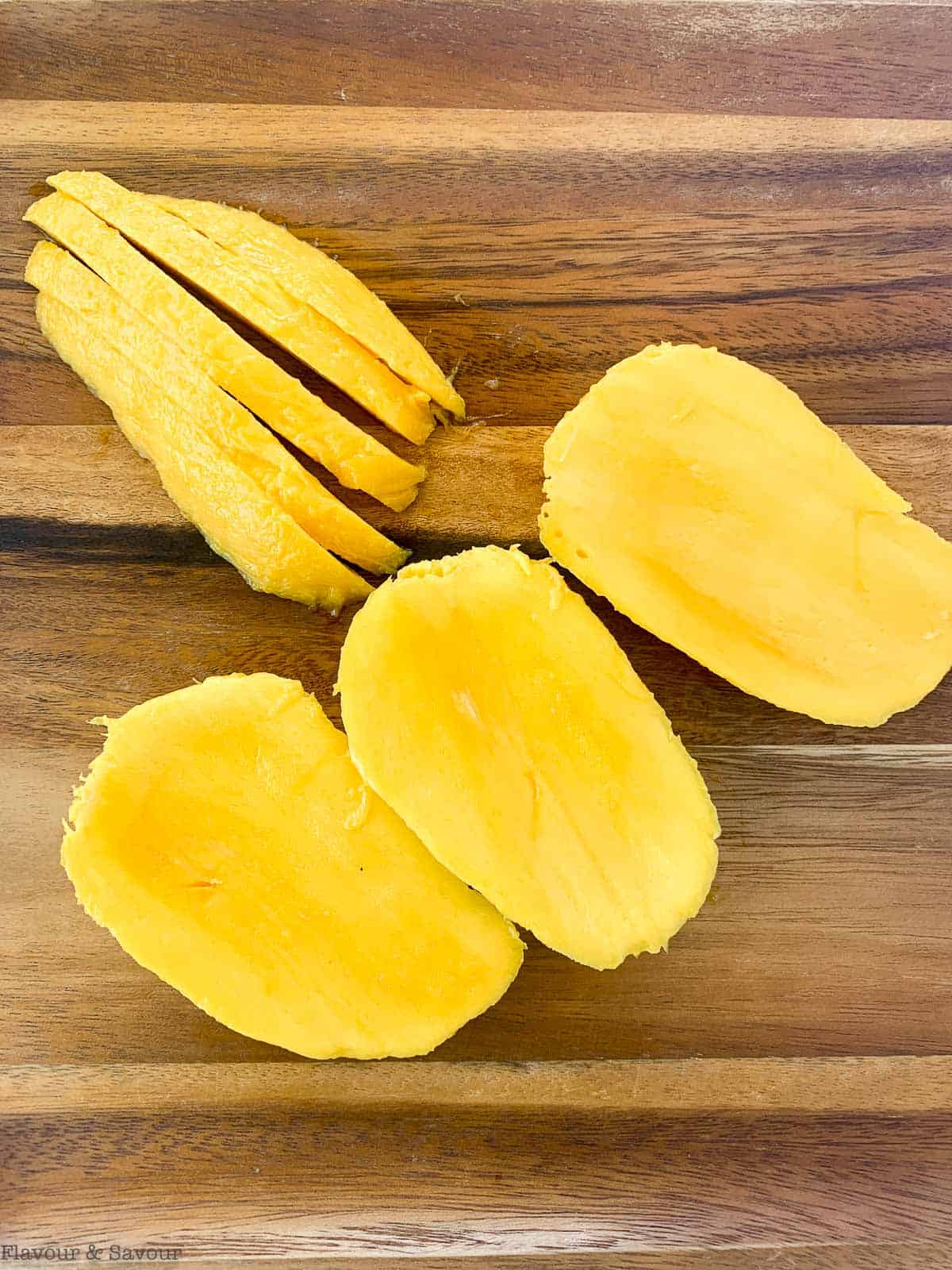 Sliced mango cheeks on a cutting board.