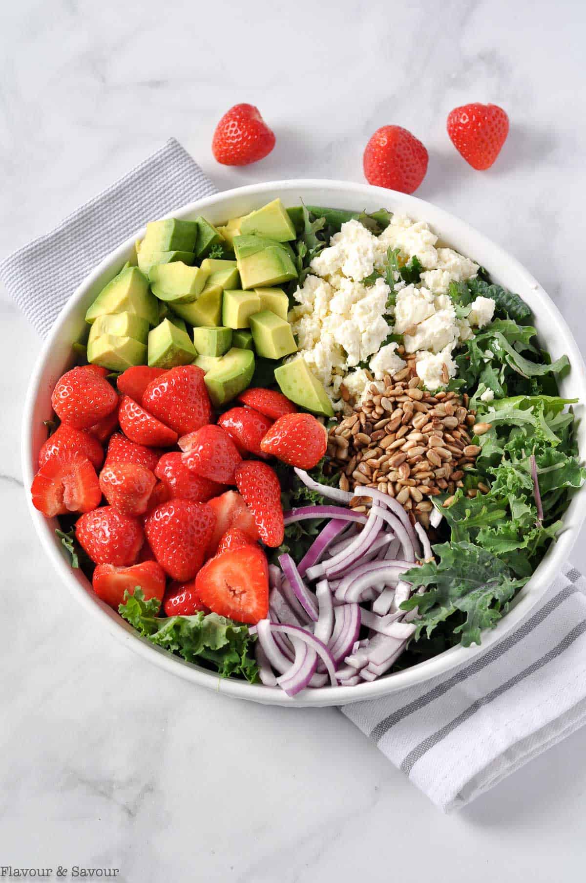 Ingredients for Strawberry Kale Salad in sections in a round white dish