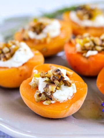 a plate with fresh apricots topped with goat cheese, walnuts and honey