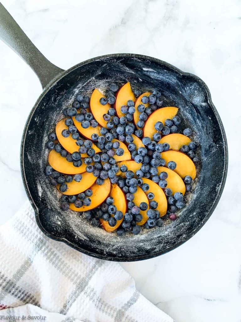 Peaches and blueberries arranged in a cast iron skillet