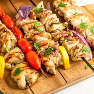 Greek Lemon Chicken Kabobs on a cutting board with lemon slices