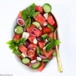 Greek Watermelon Basil Salad in an oval bowl with a gold spoon
