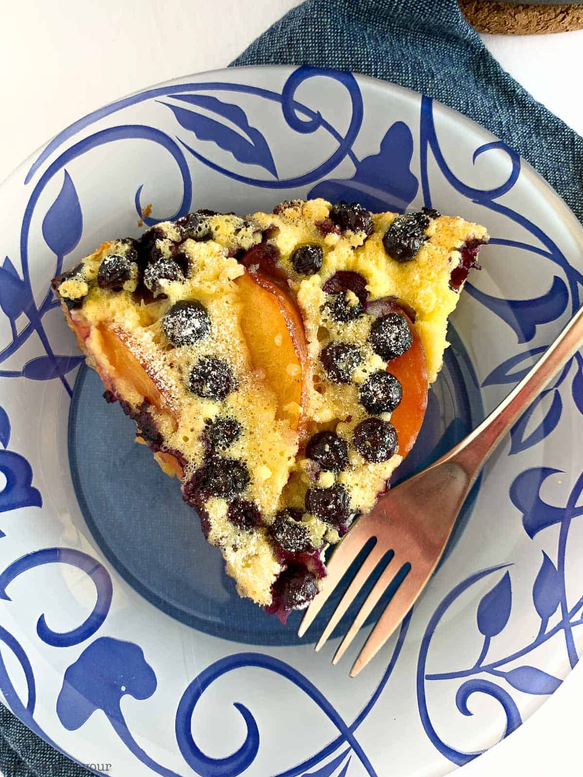 Close up view of Gluten-Free Blueberry Peach Clafoutis on a blue patterned plate