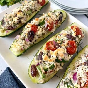 Greek chicken stuffed zucchini boats on a platter.