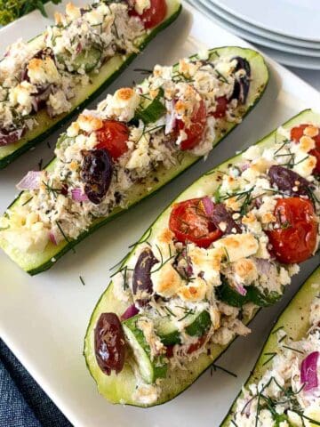 Greek chicken stuffed zucchini boats on a platter.