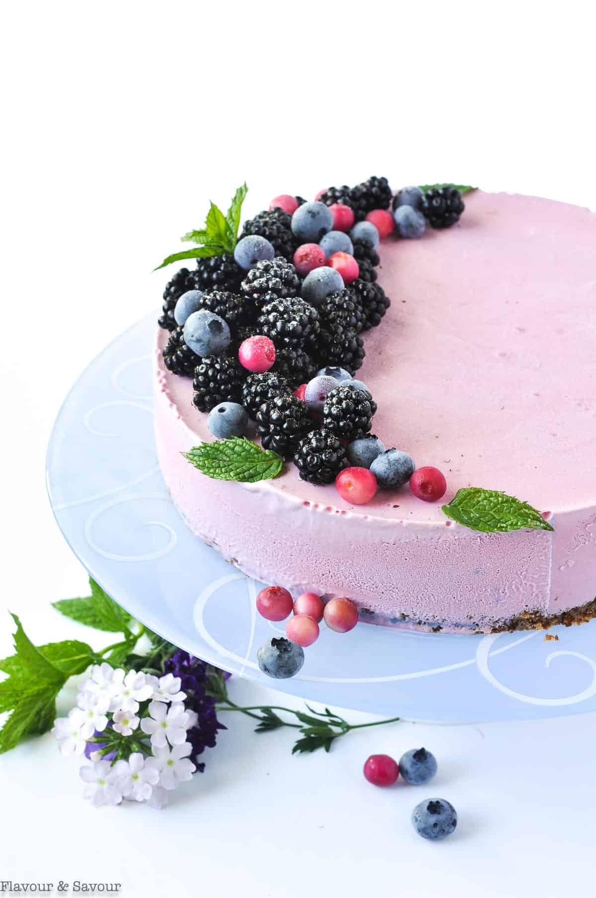 Blackberry Ice Cream Cheesecake decorated with berries on a pale blue plate.