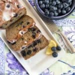 Grain-Free Blueberry Banana Bread sliced next to a bowl of fresh blueberries