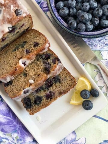 Grain-Free Blueberry Banana Bread sliced next to a bowl of fresh blueberries