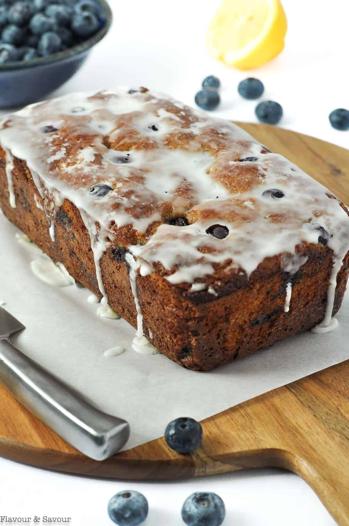 A loaf of blueberry banana bread with lemon glaze drips