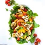 Overhead square image of grilled Halloumi Peach and Tomato Salad on a white background