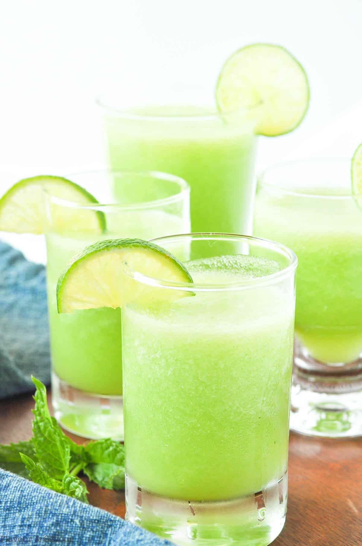 Close up view of different sized glasses of Honey Lime Mocktail with Mint sprigs and lime slices