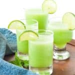 Four glasses of honeydew lime mocktail with lime slices for garnish