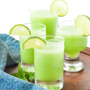 Four glasses of honeydew lime mocktail with lime slices for garnish