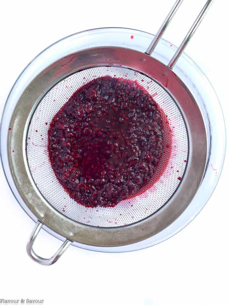 Blackberries in a sieve to strain for Blackberry Cheesecake Ice Cream Cake