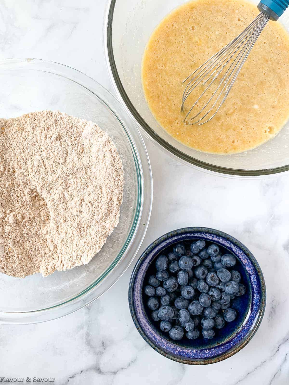 Wet and dry ingredients for Blueberry Banana Bread in two glass bowls