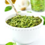 a small bowl of basil cashew pesto with a spoon