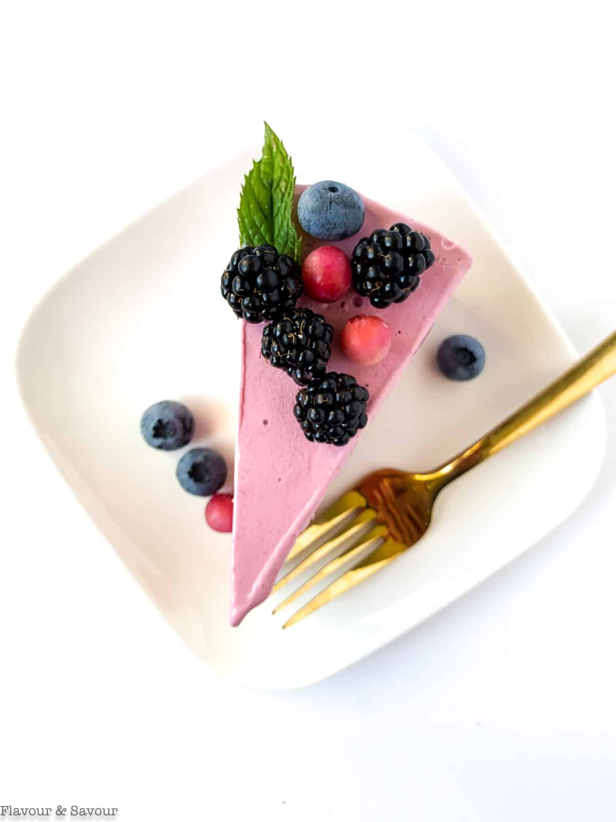 a slice of Blackberry Ice Cream Cheesecake on a place decorated with berries and a mint leaf