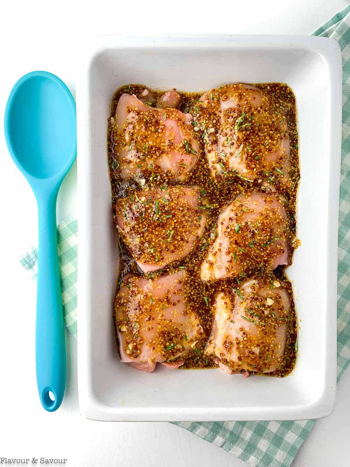 Maple Dijon chicken thighs in a baking dish covered in sauce.