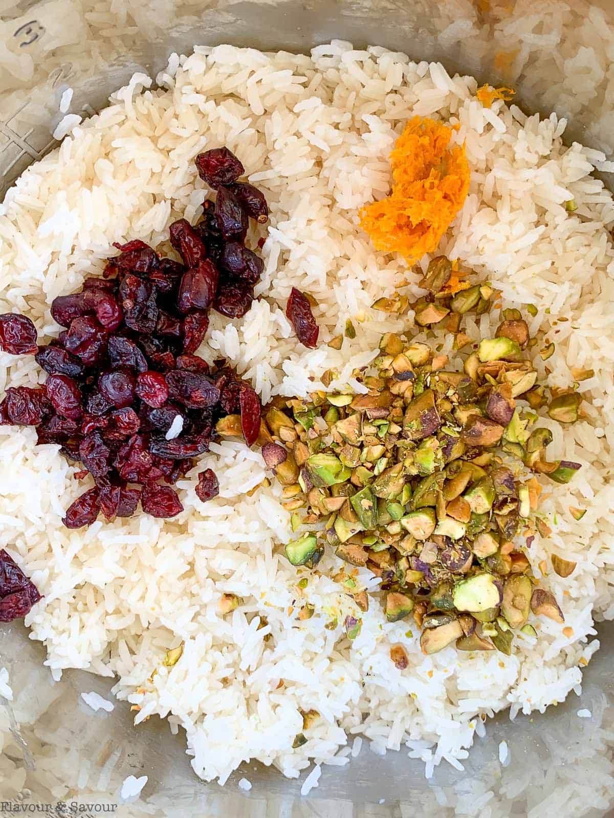 Adding cranberries, pistachio and orange zest to cooked rice.