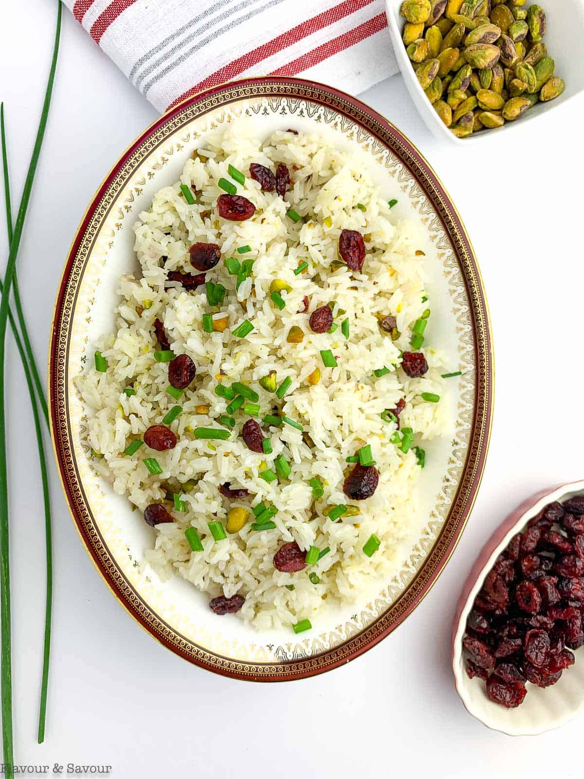 an oval bowl of Instant Pot Cranberry Pistachio Jasmine Rice with small bowls of pistachios and cranberries beside