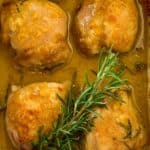 Easy Baked Maple Dijon Chicken in baking dish with a sprig of rosemary