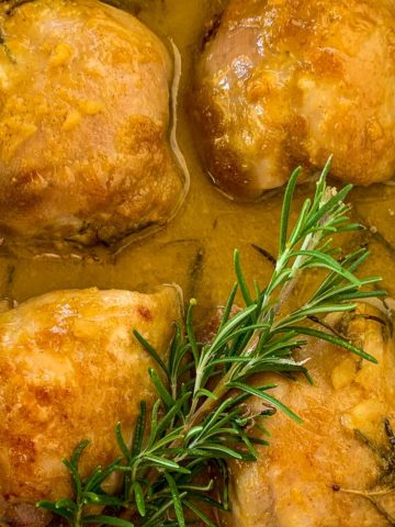 Easy Baked Maple Dijon Chicken in baking dish with a sprig of rosemary