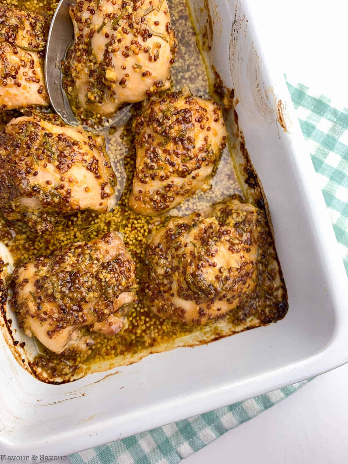 Maple Dijon Chicken Thighs with grainy mustard. baked in a casserole dish.