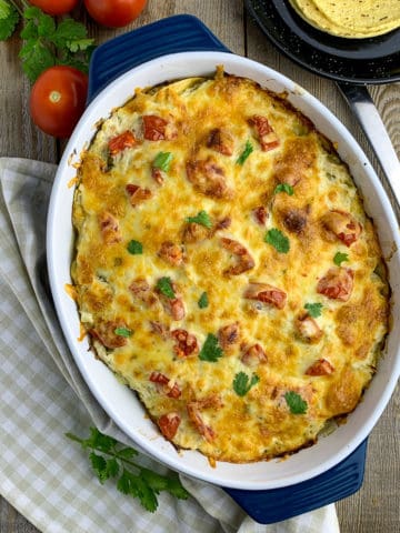 Overhead view of Salsa Verde Chicken Tortilla Casserole in a baking dish with tortillas in the background