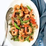 Overhead view of Shrimp and Snow Pea Stir Fry in a white serving bowl with a spoon