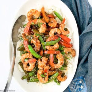 Overhead view of Shrimp and Snow Pea Stir Fry in a white serving bowl with a spoon