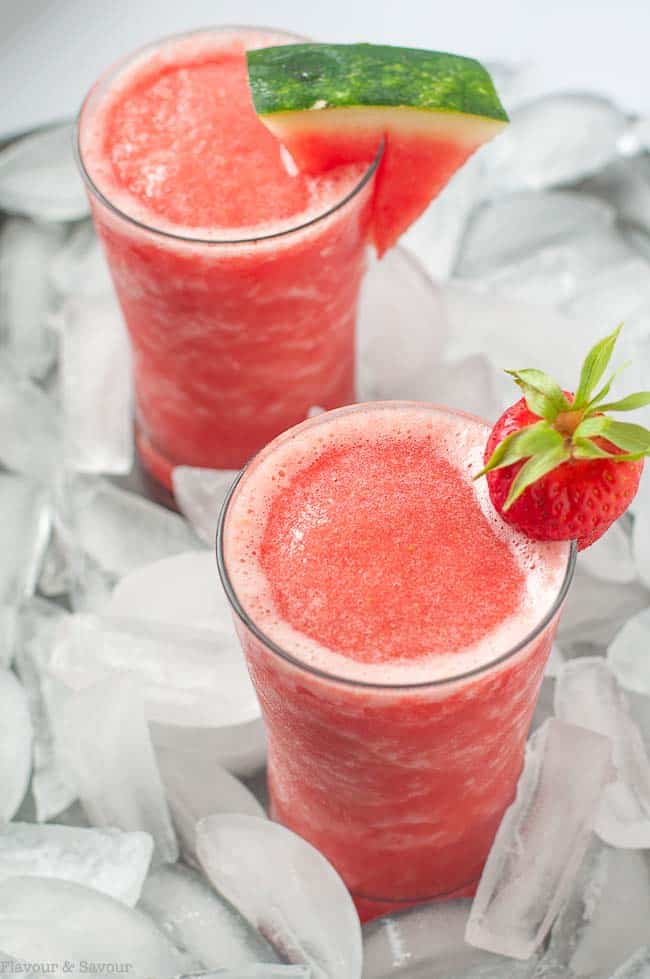 Two glasses of strawberry watermelon sangria slushie garnished with watermelon.