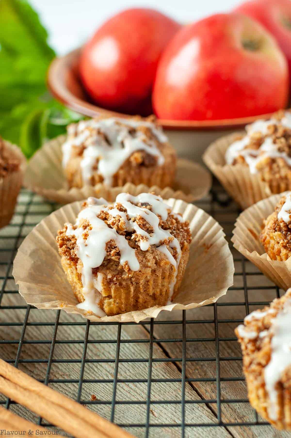 Glazed Apple Muffins with a bowl of apples in the background