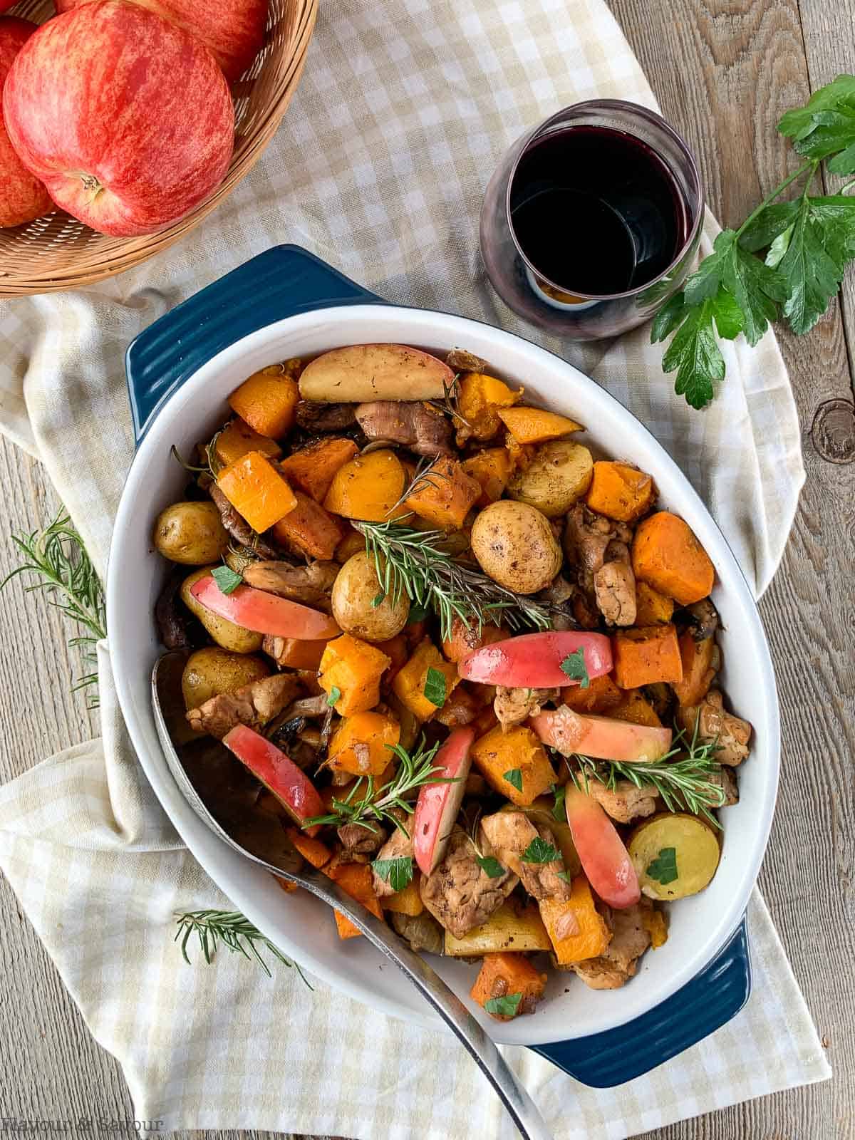 A serving bowl with harvest chicken with bacon and rosemary.