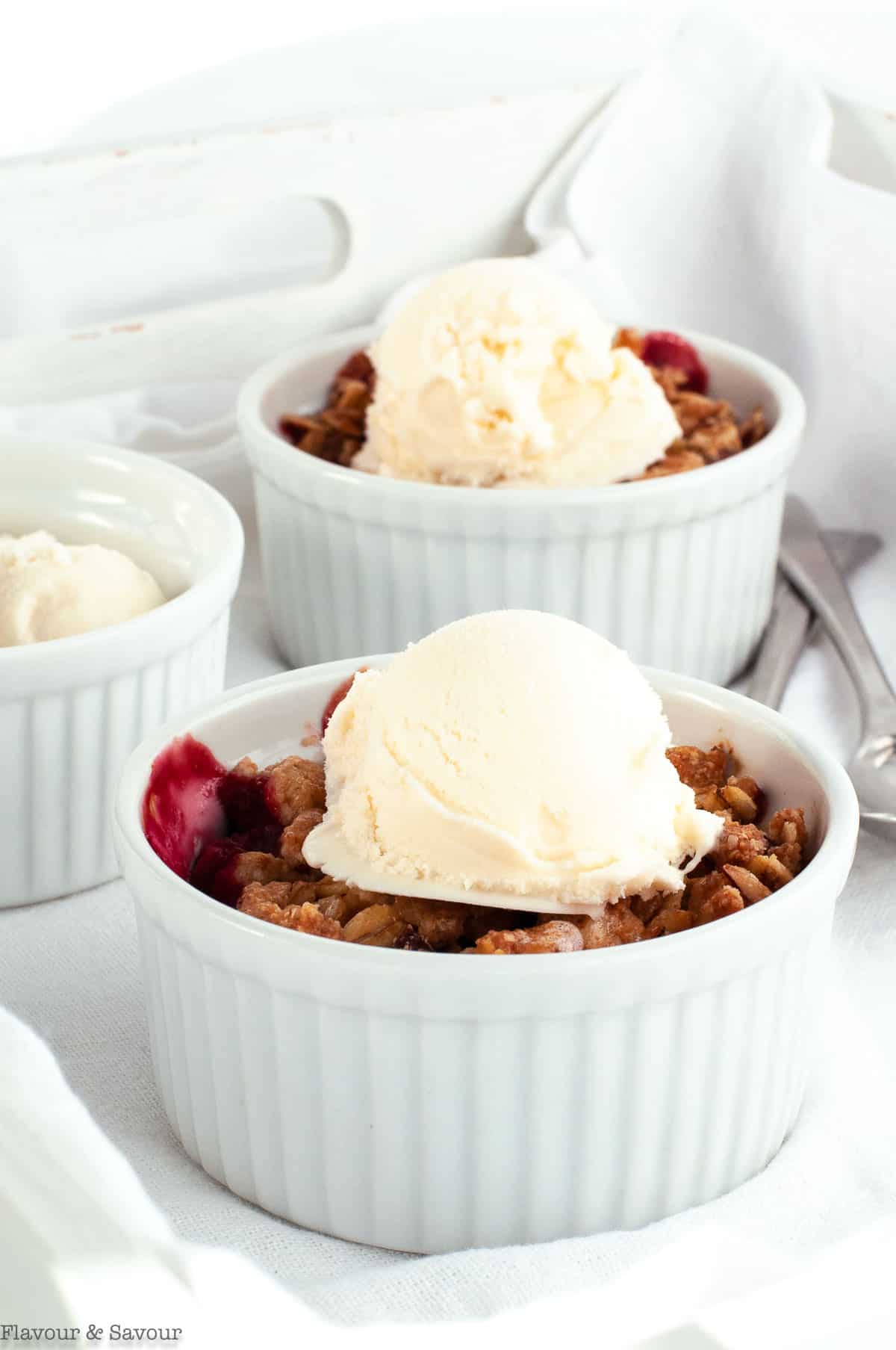 Two ramekins with mini Cherry Almond Crisp with ice cream