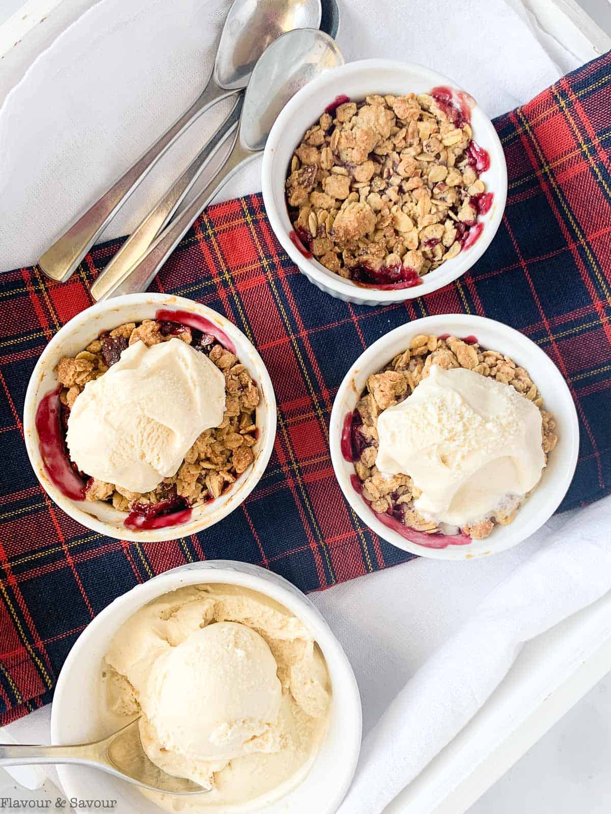 Overhead view of 3 ramekins with cherry crisp and a bowl of ice cream