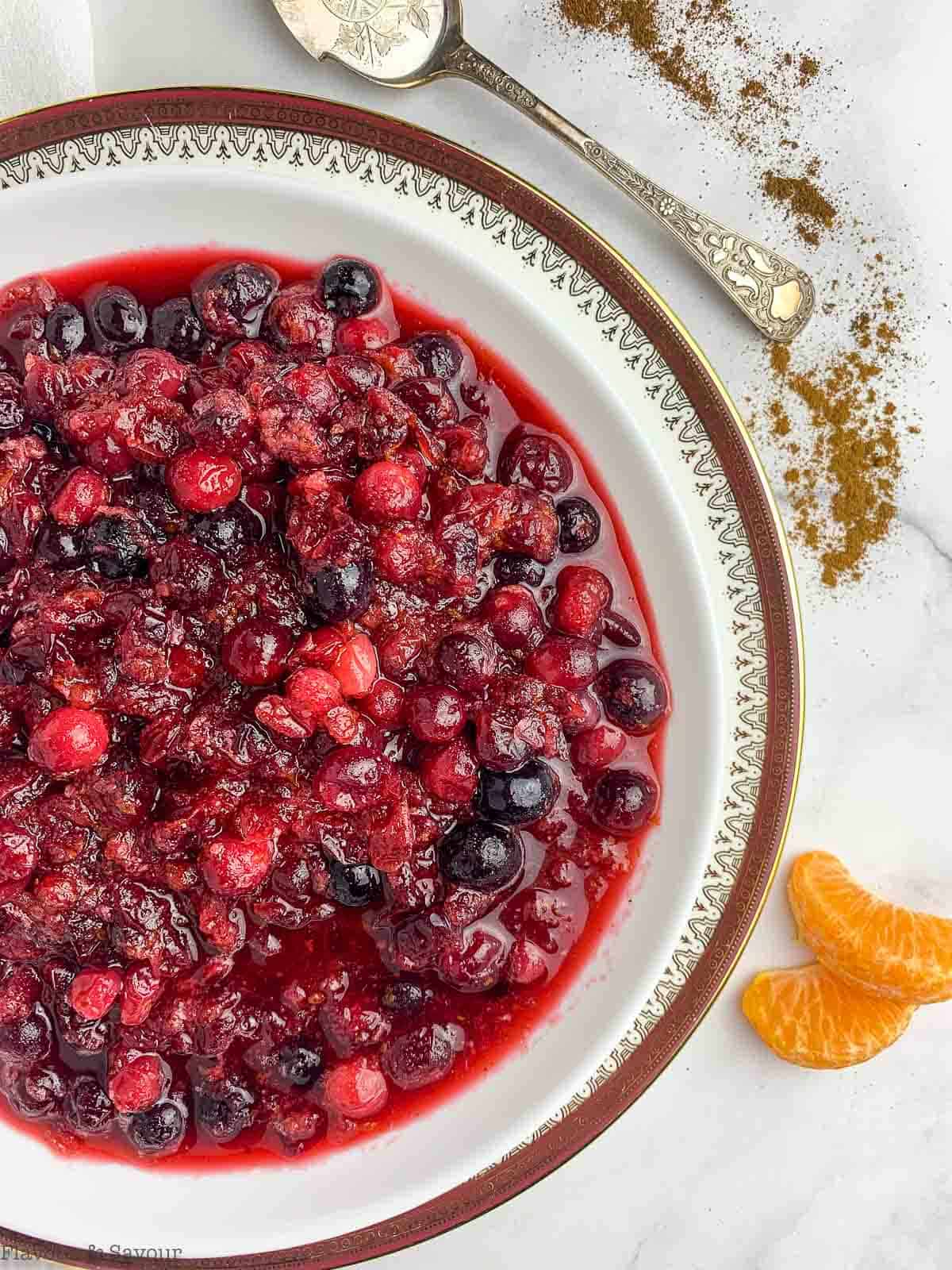 Close up overhead view of a bowl of Cranberry Orange Sauce with orange segments beside
