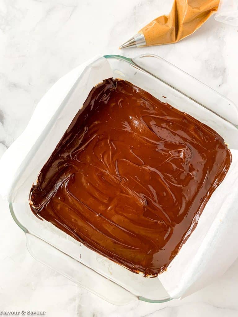Spreading melted chocolate on peanut butter base