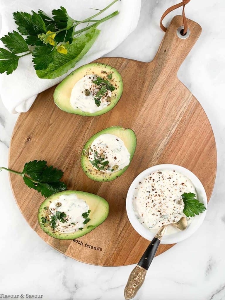 Stuffed Avocados with Creamy Herb Sour Cream Dip on a round serving board