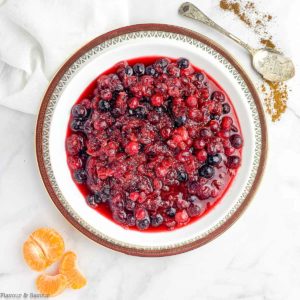 A bowl of Cranberry-Orange Sauce with orange segments beside and a spoon