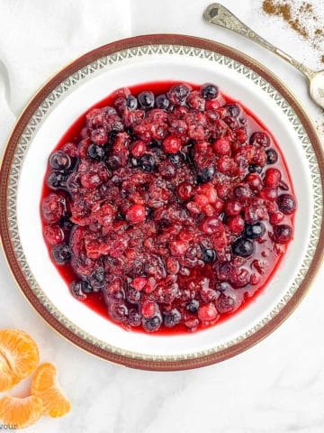 A bowl of Cranberry-Orange Sauce with orange segments beside and a spoon