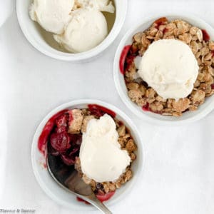 Two ramekins with Cherry Almond Crisp with a dish of ice cream