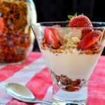 Close up view of a glass of granola with yogurt and strawberries