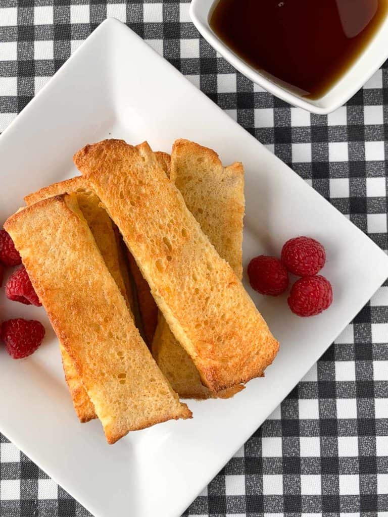 overhead view of air fryer French toast sticks with raspberries