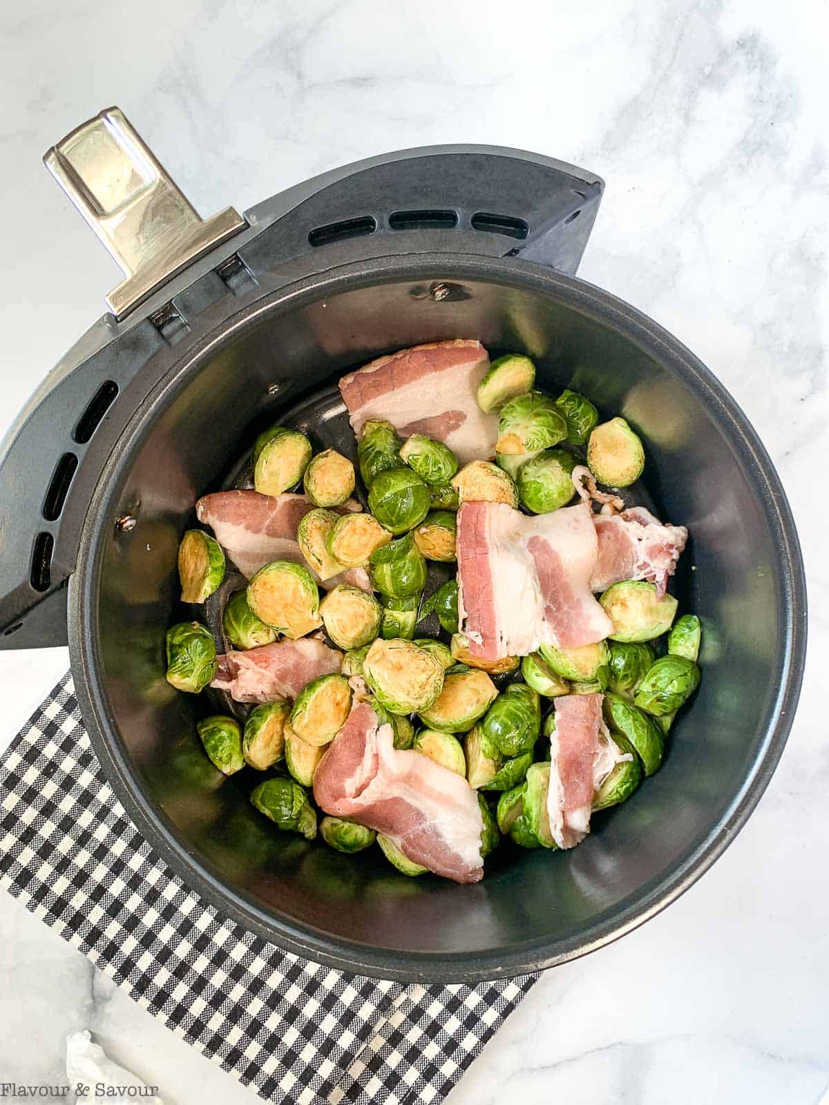 Brussesls sprouts with bacon in air fryer basket before frying