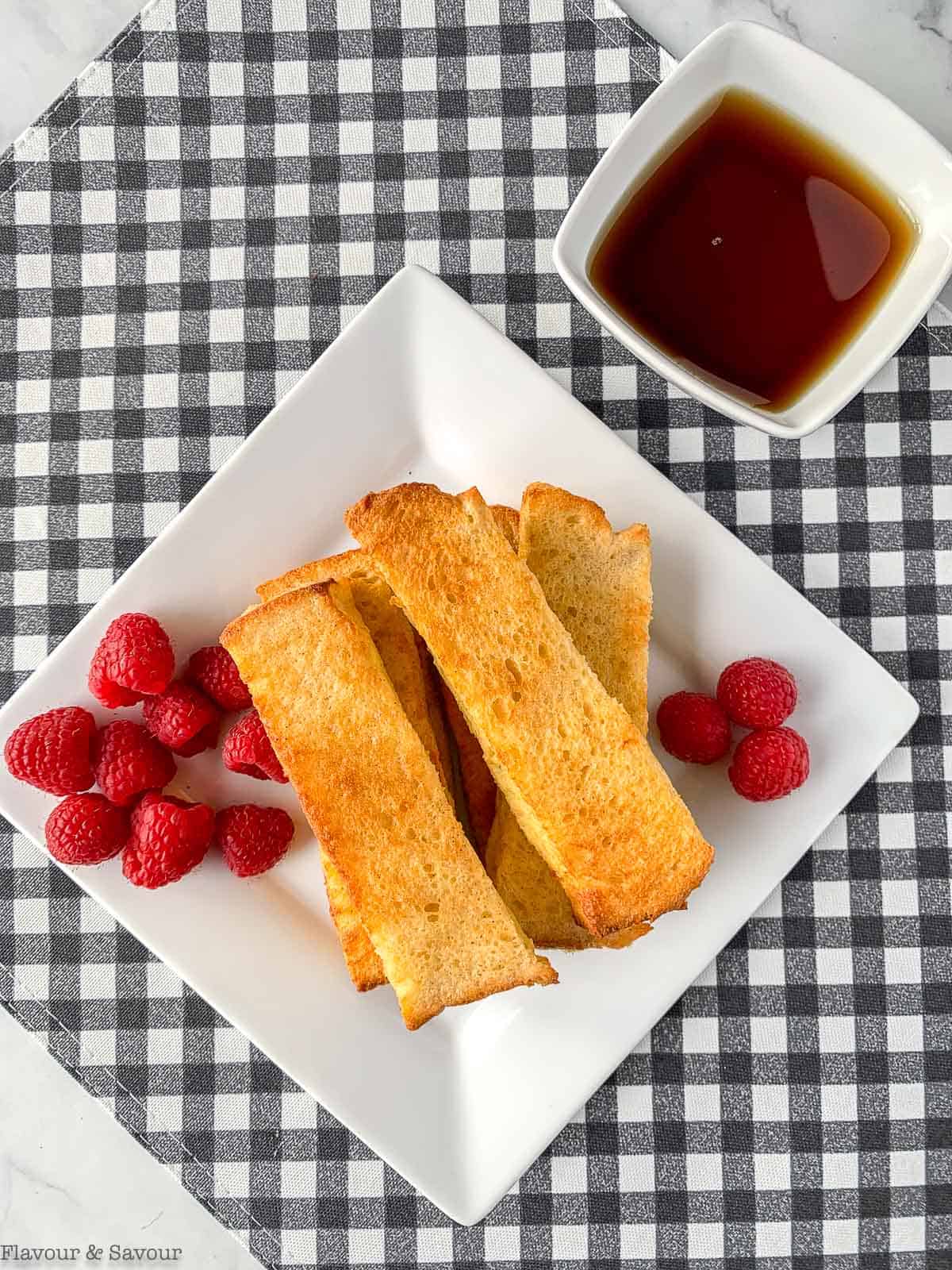 Cinnamon French Toast sticks with raspberries and a bowl of maple syrup