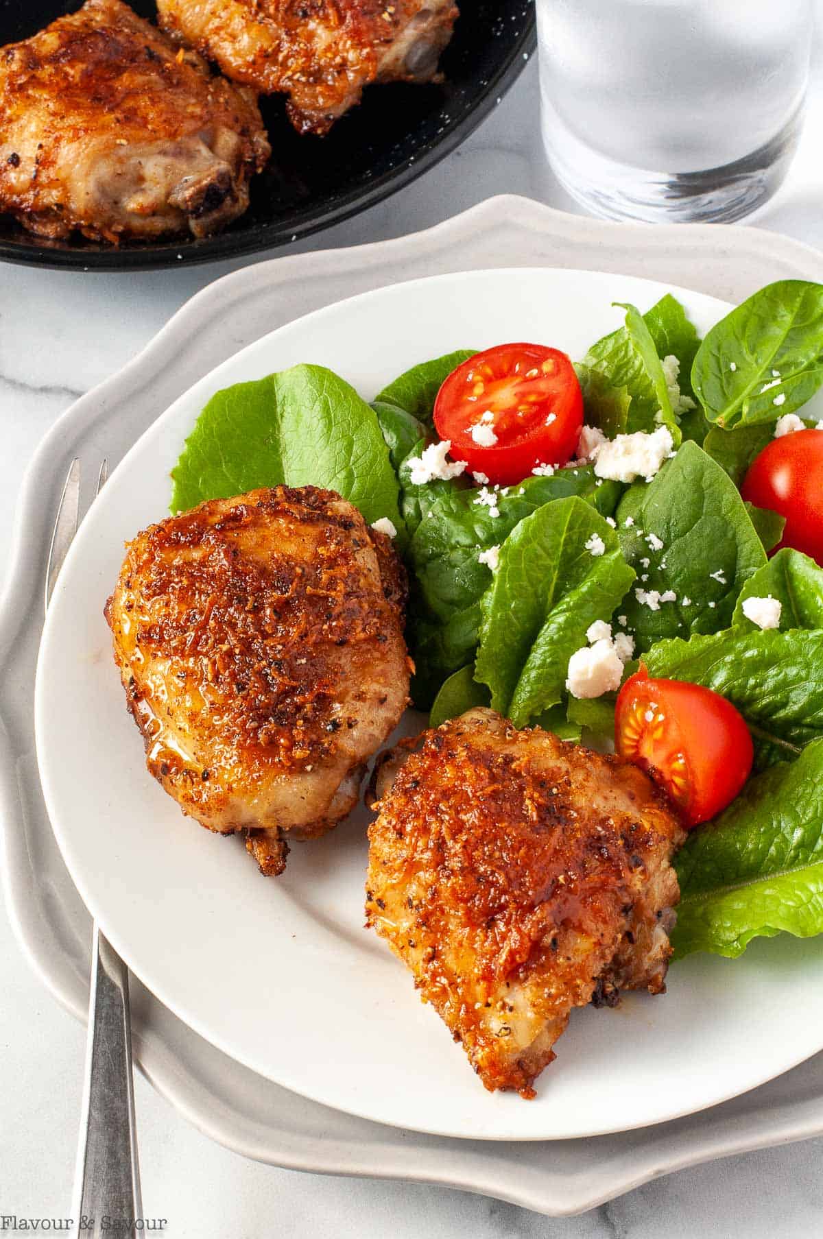Garlic Parmesan Chicken Thighs on a plate with a green salad