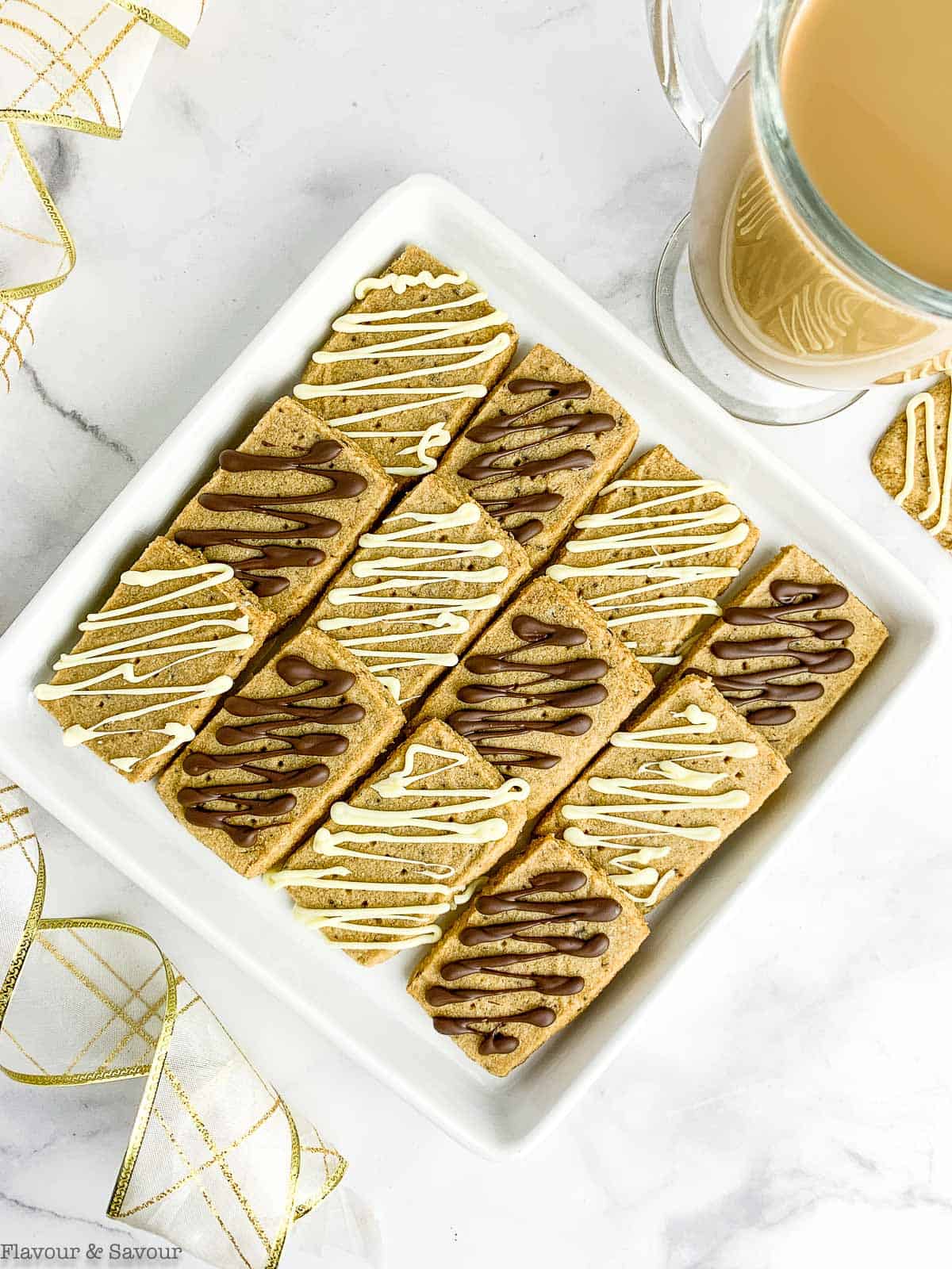 Overhead view of chocolate drizzled espresso shortbread cookies with a cup of coffee.