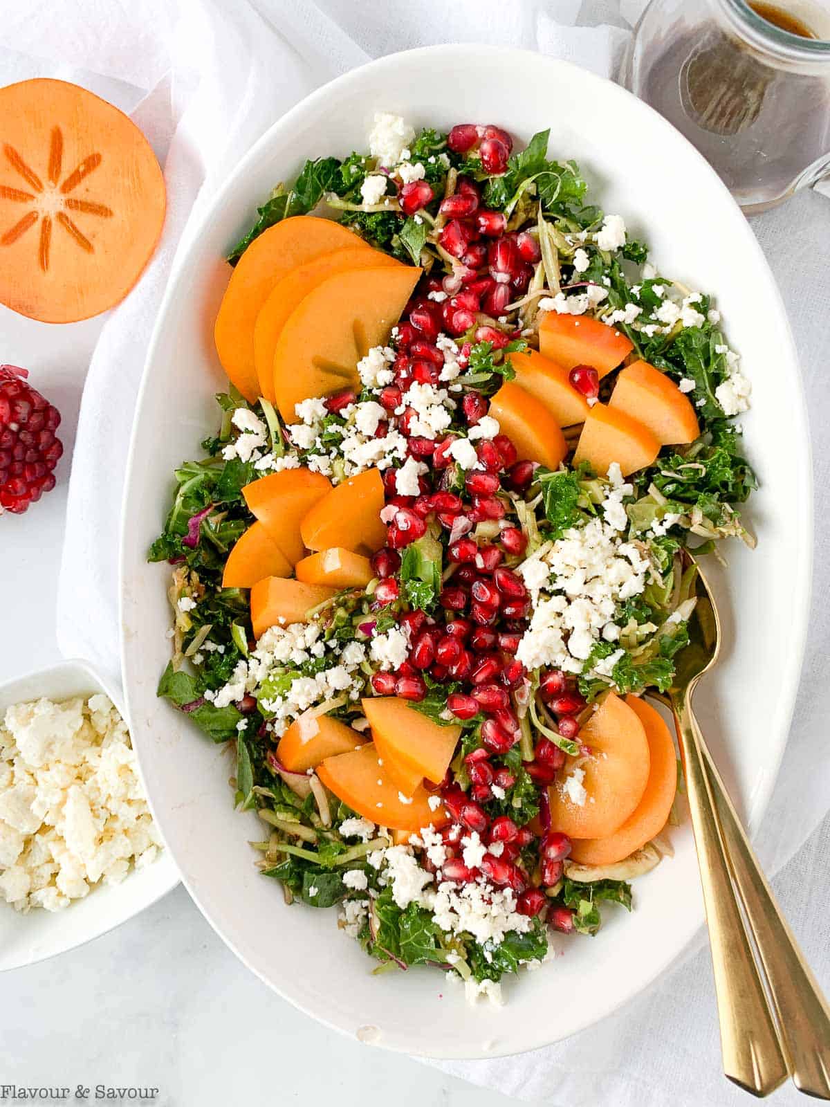 Winter Pomegranate Persimmon Kale Salad with sliced persimmons, feta cheese and pomegranate arils.
