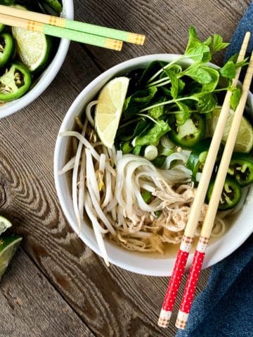 Overhead view of Chicken Pho with red chopsticks