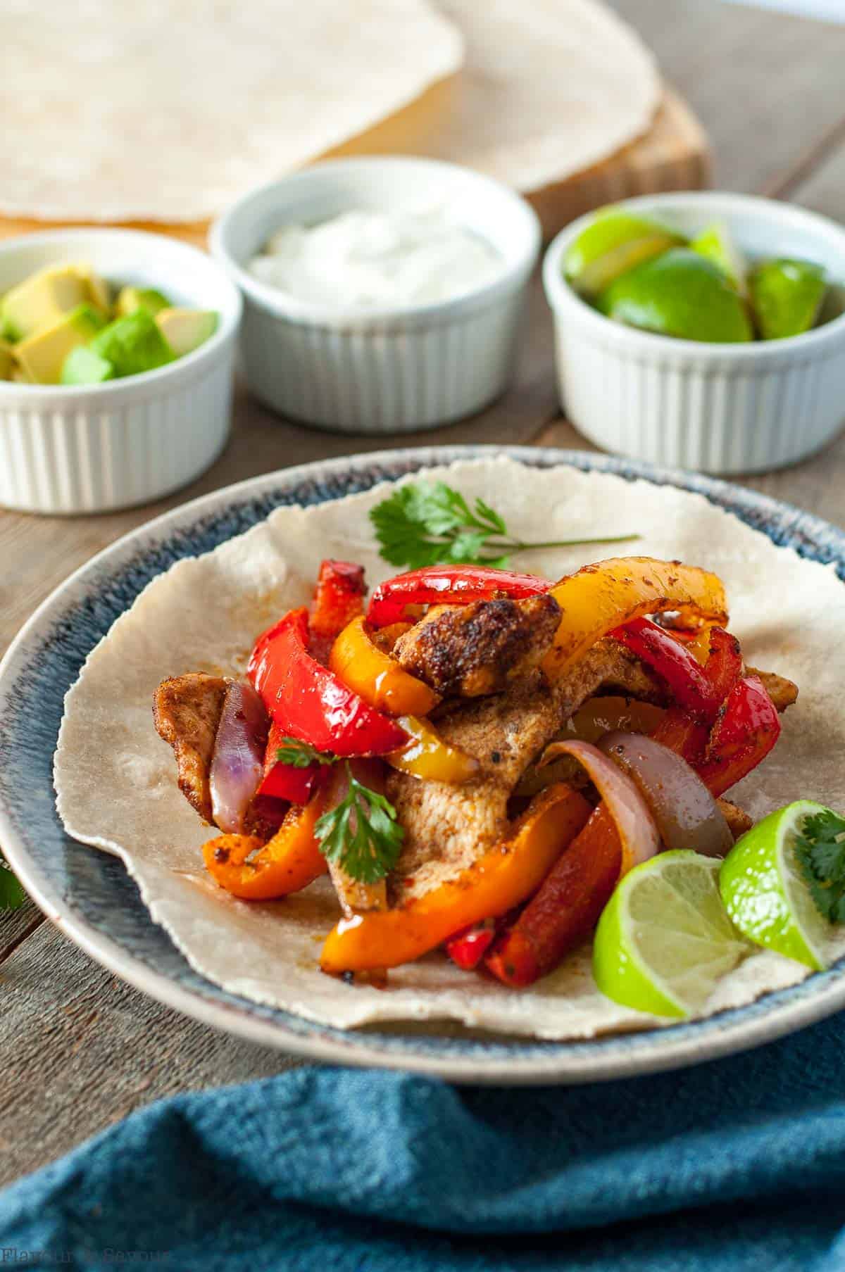 Side view of chicken fajitas dinner with small bowls of toppings